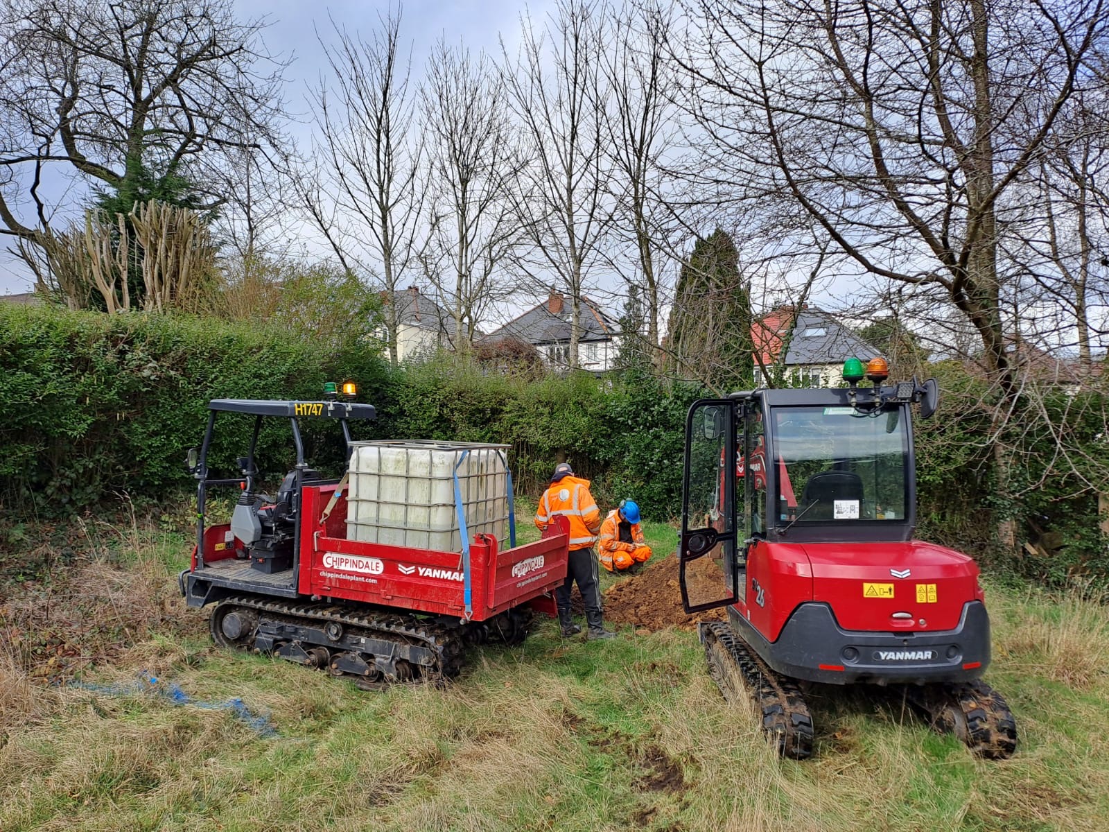 Mini excavator and tracked dumper with workers digging trench on residential garden site in Leeds